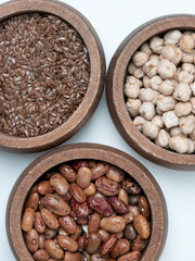 Assorted flax seeds chickpeas and pinto beans in wooden bowls on white background