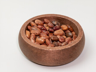Assorted dried beans in a rustic wooden bowl on white background