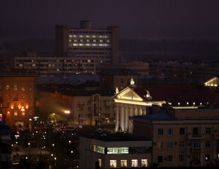 Obraz premium Dusk settles over the city, highlighting illuminated structures and bustling streets below