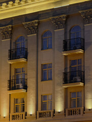 Fototapeta premium Warm lights illuminate the ornate balconies and windows of a historic building at night