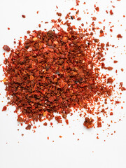 Crushed red pepper flakes scattered on white background