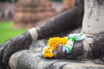 Flower offerings on a ruined Buddha sculpture in Ayutthaya, Thailand