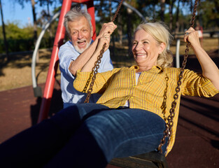 Happy active senior woman having fun on a swing in park outdoors