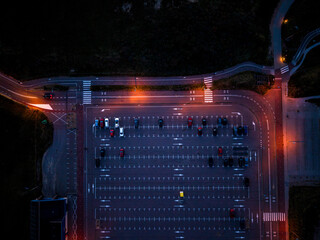 Aerial nighttime view of empty parking lot warm orange streetlights illuminate marked lanes and...