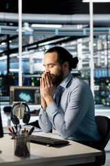 Engineer in data center sitting with eyes closed, managing stress after long troubleshooting session on critical systems. Server hub admin recollecting himself after repeated debugging attempts