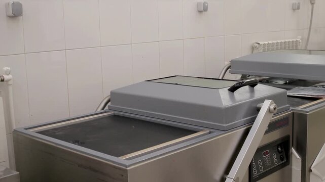 A worker at a production facility packs fish into a vacuum bag using equipment