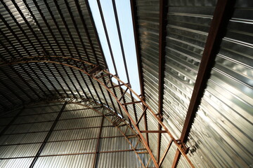 Obraz premium Modern metal hangar roof with steel beams and corrugated panels, industrial architecture background 