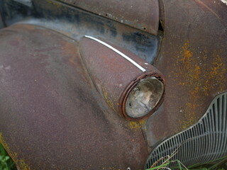 Close up of rusty vintage car headlight and fender with patina texture, old vehicle decay concept
