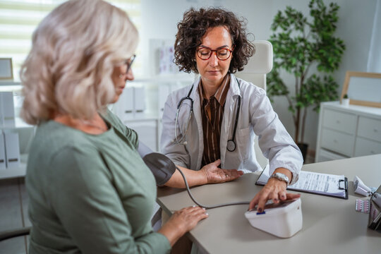 Female doctor checking blood pressure of senior woman in the doctors office