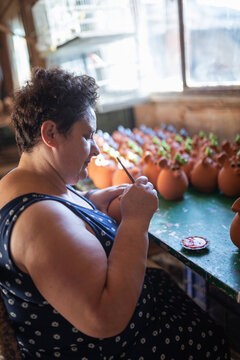 Female artisan painting piggy banks in pottery workshop
