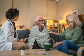 Elderly man having temperature measured by female doctor during home visit