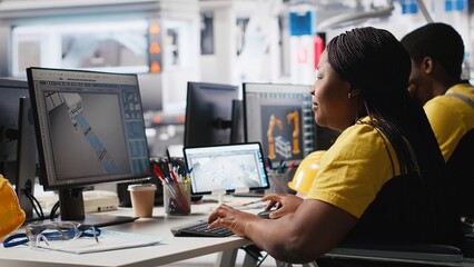 Photovoltaics factory engineer wheelchair user improving solar panels on an industrial software, working on computer for the manufacturing industry. Renewable energy. Camera A