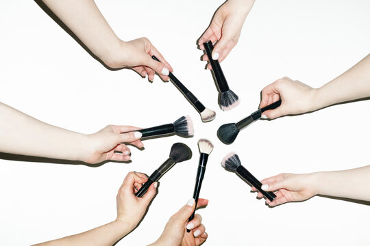 Hands holding various make up beauty brushes for different products 