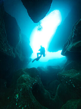 Sunlight illuminating scuba diver exploring underwater cave