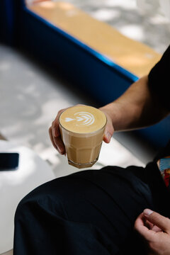 Anonymous person holding and sipping a latte art coffee
