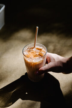 Close up of an anonymous individual holding an iced coffee