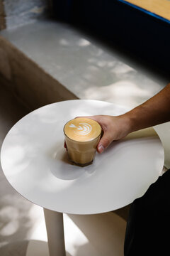 Anonymous hand holding a latte with foam art