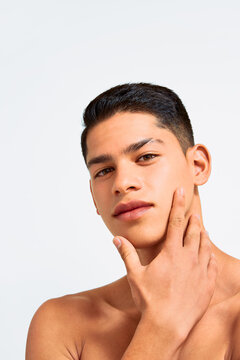 Young Latino man touching his face in skincare routine portrait
