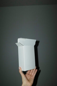Hand holding empty mockup cardboard package with space for text