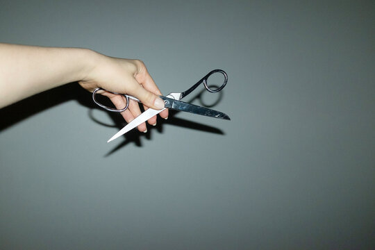 Hand holding hard metal shiny office supply scissors with flashlight