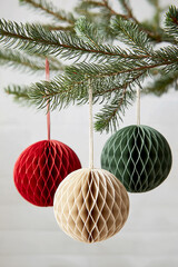 Paper Christmas balls red green and beige hanging on pine branches