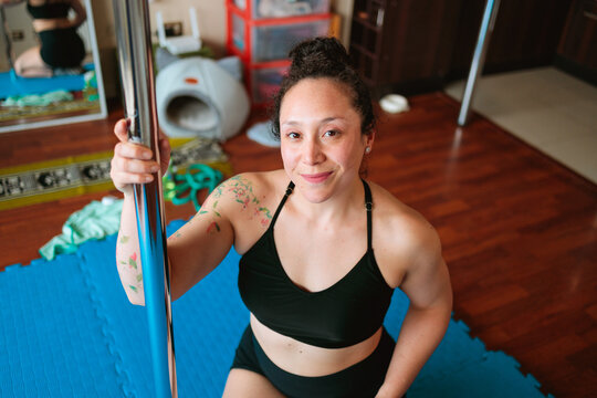 Smiling Woman Kneeling Beside Pole Indoors