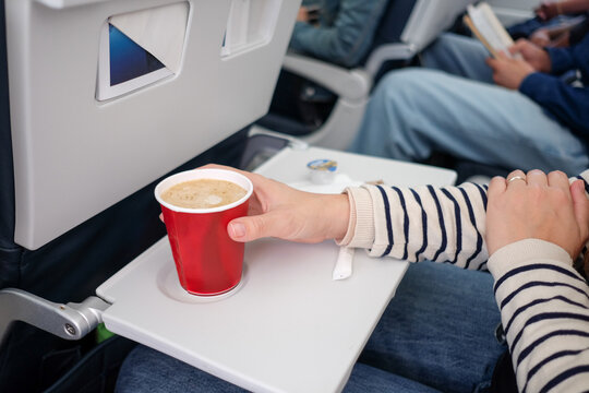 Passenger Drinking Coffee on Airplane Tray Table