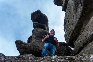 Tourist gesturing thumbs up between rock formations 