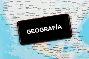 an a smart phone with a white Geografia word in spanish or geography word in english over a north american political map © Alejandro Bernal