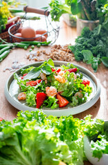 Gourmet salad with lettuce, strawberry, shrimps and walnuts on table in bright modern kitchen