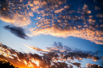 Fototapeta premium Colorful sunset sky filled with clouds over a serene landscape displaying nature's beauty at dusk