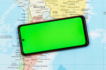 an a smart phone with a green display screen over the south of south american political map