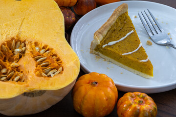 Pumpkin tart with a spider web design, surrounded by autumn decorations of pumpkins, leaves, and pinecones