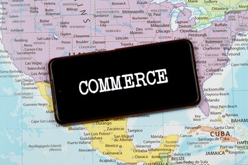an a smart phone with a white commerce word over a north american political map