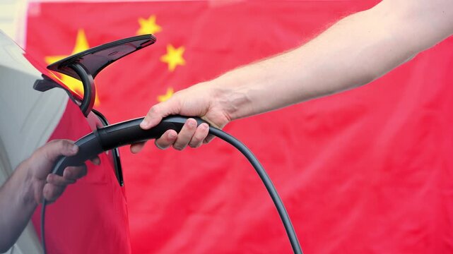Close up of electric car charging port. Plug in and disconnect of the charging port . Chinese flag background