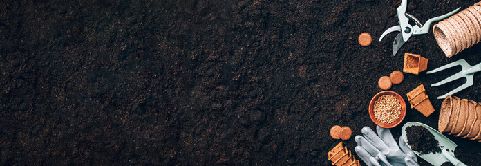 Gardening tools over soil background. Gardening tools, seeds, pruner, rake, shovel, biodegradable...