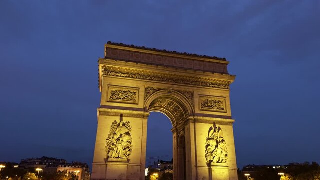The stunningly illuminated Arc de Triomphe shines magnificently at dusk in the enchanting city of Paris, France