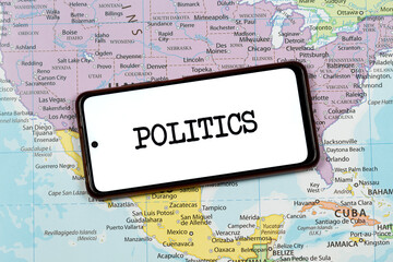 an a smart phone with a black politics word over a north american political map