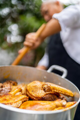 Chef cooking chicken stew in large outdoor pot