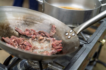 Frying fresh beef strips in a large outdoor pan