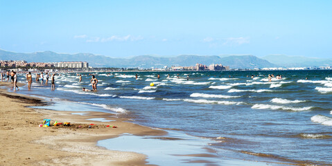 Valencia, Spain September 11 2025: Early autumn scene at a popular beach near Valencia, Spain. Despite the end of summer, many people are seen enjoying the sunny weather and the sea
