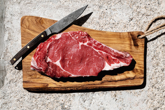 Freshly Cut Ribeye Steak on Wooden Board and knife