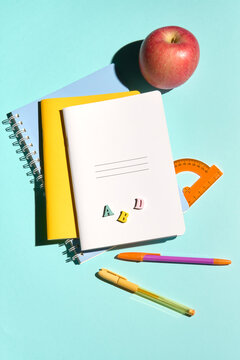 Colorful School Supplies and an Apple on a Light Blue Background
