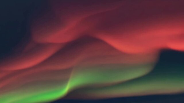 A mystical and ethereal video of swirling green and red aurora borealis light in a dark night sky, creating a serene and abstract natural spectacle