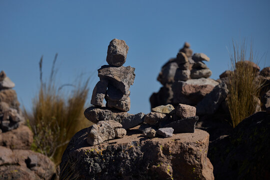 Stone apachetas stand as ancient offerings against the backdrop of the majestic Ampato and smoking Sabancaya volcanoes, symbols of Andean spirituality and enduring tradition