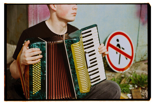 Musician with accordion by no trespassing sign