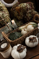 Autumn harvest. a wicker basket with a green pumpkin and white decorative pumpkins on a wooden table with candles on a background of hydrangeas.