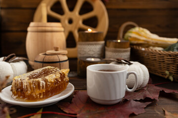 Fototapeta premium lose-up of a honeycomb on a white plate surrounded by a wooden barrel and a cup. a warm and rustic atmosphere. Bee honey.