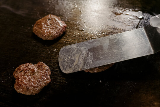 Cooking beef patties on a griddle inside a kitchen