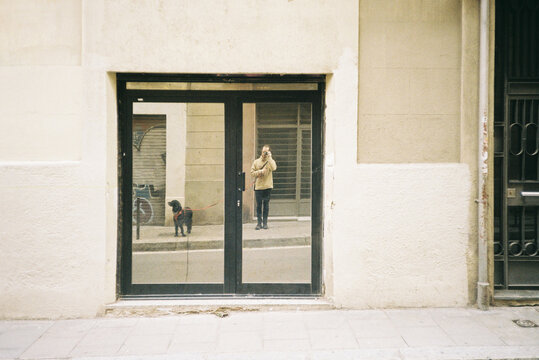 Reflections of a Person and a Dog on a City Street